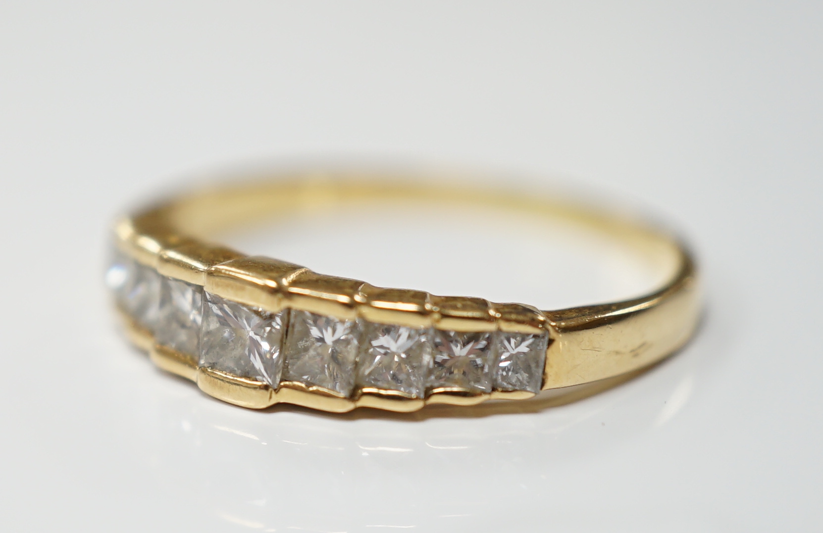 A modern 18ct gold and graduated nine stone princess cut diamond set half hoop ring, size L, gross weight 1.9 grams.
